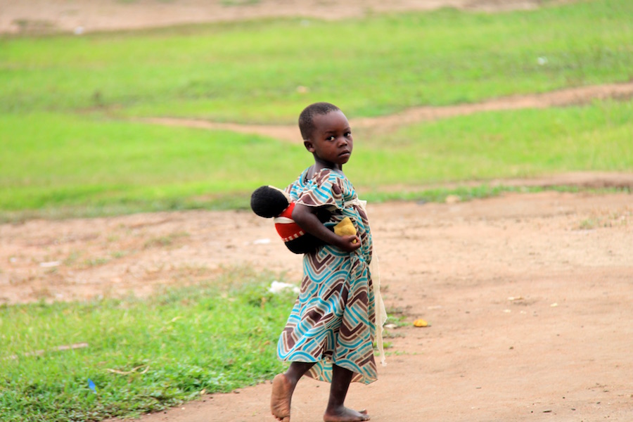 Little girl copies mummy carrying her doll on her back